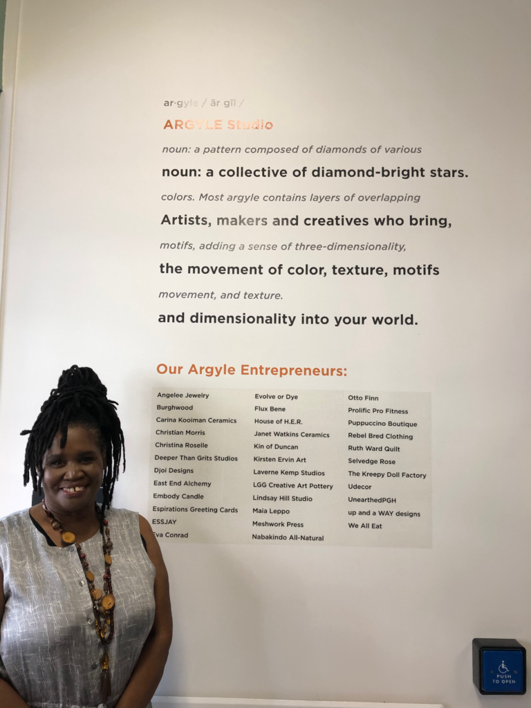 Christine McCray-Bethea, co-founder of Argyle Studio standing in front of a display of entrepreneurs.