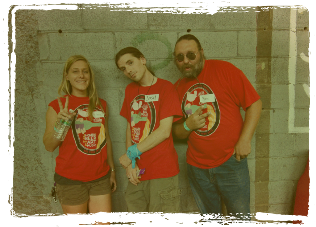 Volunteers in red shirts pose in front of a block wall in the CJ warehouse.