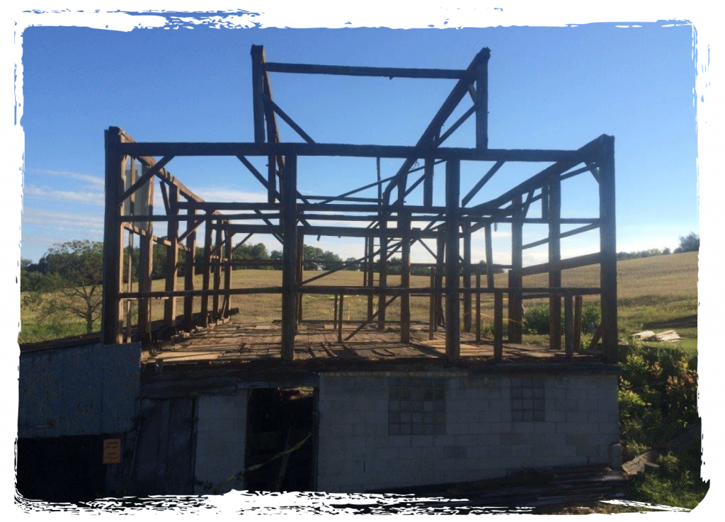 Deconstruction project of a barn house with only framing and foundation still standing.